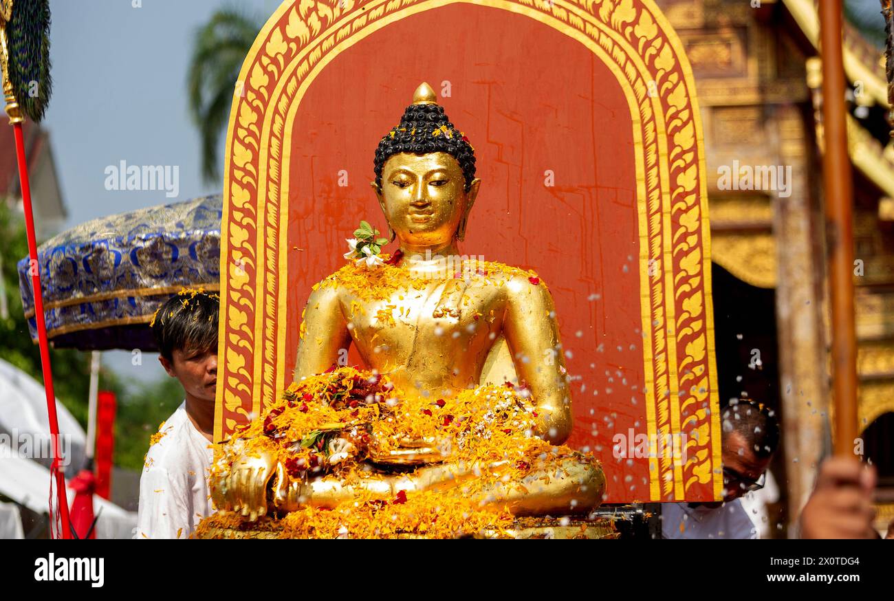 I thailandesi offrono fiori durante la processione della statua del Buddha Sihing di Phra Buddha per celebrare le celebrazioni di Songkran al tempio Wat Phra Singh Woramahaviharn. Il festoso Songkran è anche conosciuto come il festival dell'acqua che viene celebrato ogni anno il 13 aprile nel tradizionale Capodanno tailandese spruzzando acqua e gettando polvere a vicenda come segno simbolico di pulizia e lavaggio dei peccati dell'anno passato. Foto Stock