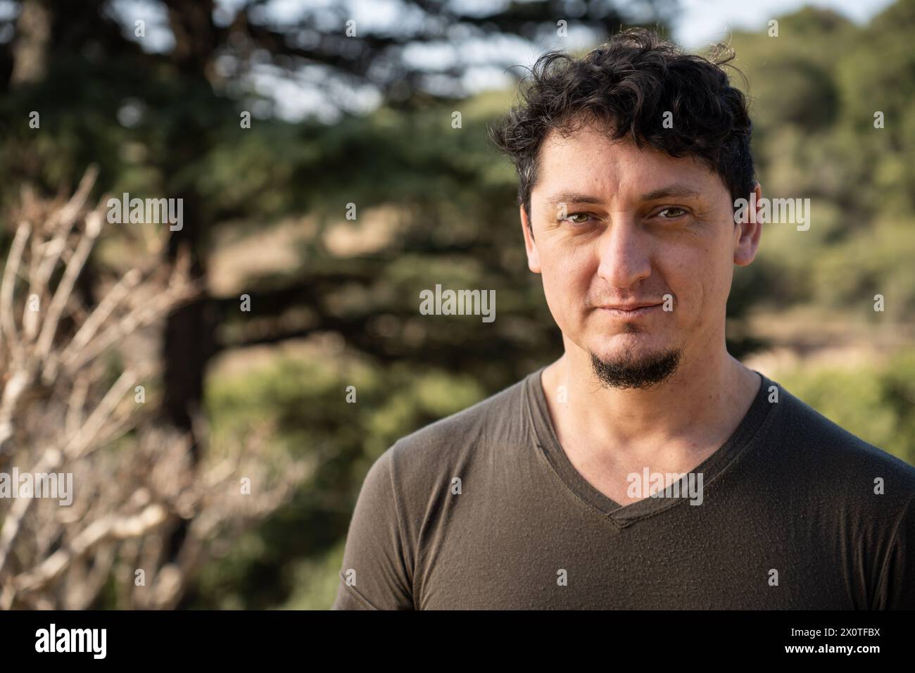 Ritratto ravvicinato di un uomo caucasico di mezza età con uno sguardo e un leggero sorriso all'aperto. Foto Stock