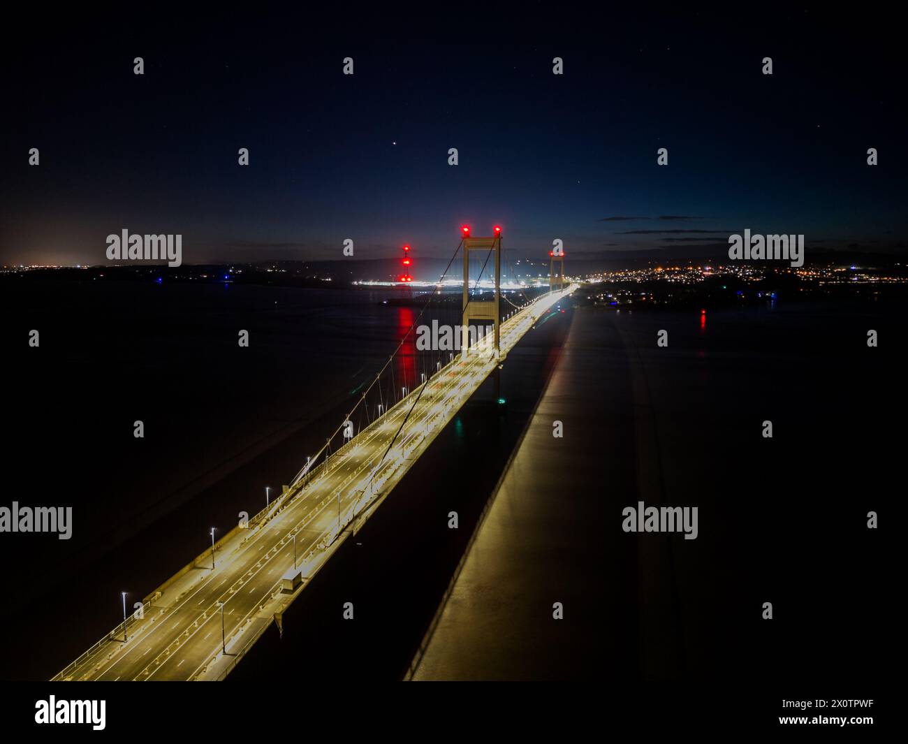 Ripresa notturna aerea che cattura le luci vibranti di un ponte sospeso contro un cielo scuro Foto Stock