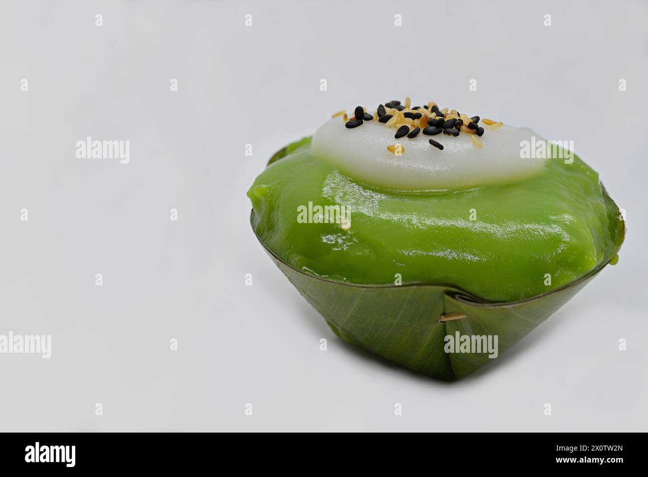 Primo piano di un dessert tailandese Khanom Tako "capovolto", con tè verde e semi di sesamo spolverati sulla crema di cocco Foto Stock