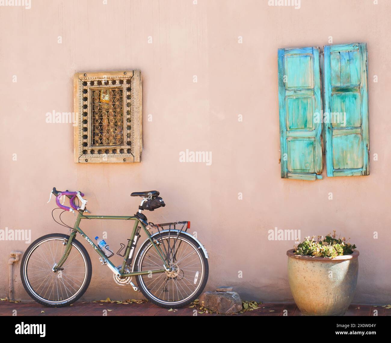 Nuova bicicletta contro un edificio in adobe con una finestra in legno turchese. Foto Stock