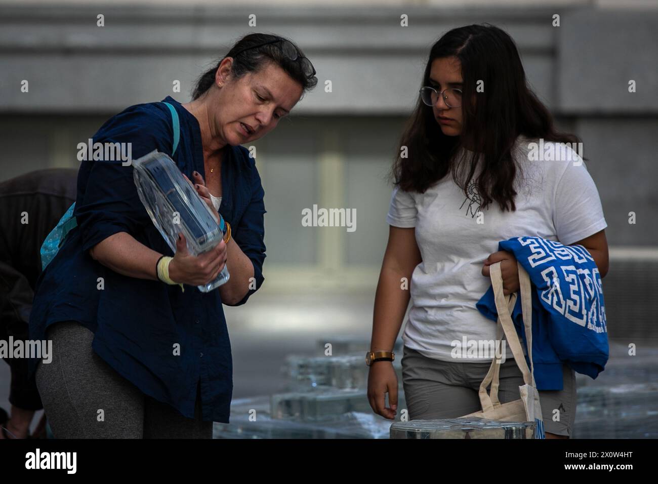 Madrid, Spagna. 13 aprile 2024. Un paio di donne sceglie un pezzo di vetro dal monumento 11M distribuito dal Consiglio comunale. Questo sabato 13 aprile, il Consiglio comunale di Madrid ha distribuito circa 6.000 pezzi di vetro dal monumento commemorativo agli attentati terroristici di Madrid dell'11 marzo 2004, smantellati per l'ampliamento della linea, nella Galleria di cristallo del Palazzo delle Cibele. 11 della metropolitana di Madrid qualche settimana fa. Credito: SOPA Images Limited/Alamy Live News Foto Stock