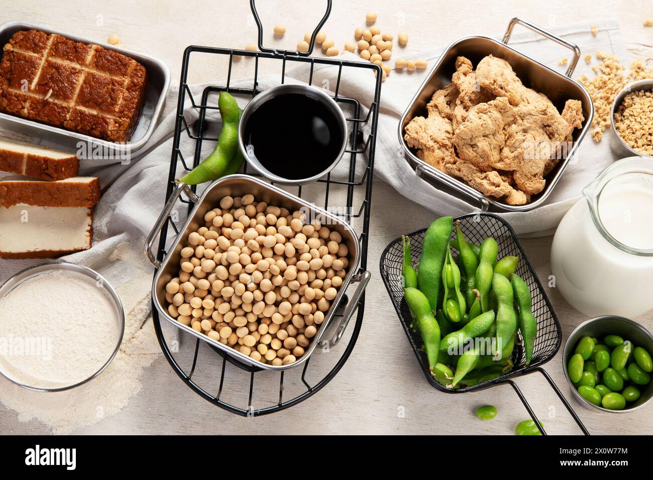 Vari prodotti di soia con semi di soia, tofu, salsa di soia e latte di soia su sfondo chiaro. Vista dall'alto Foto Stock