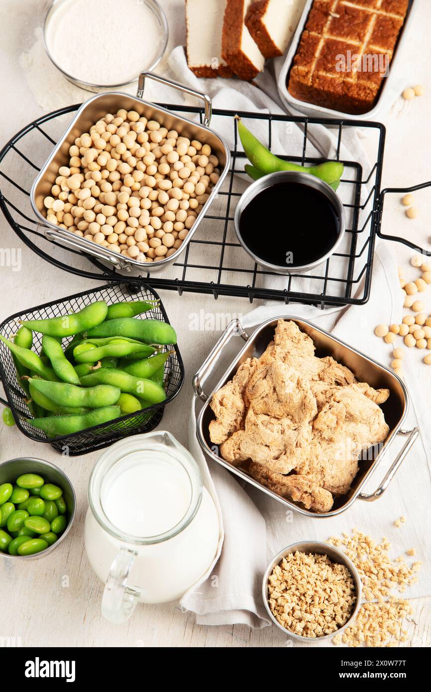 Vari prodotti di soia con semi di soia, tofu, salsa di soia e latte di soia su sfondo chiaro. Vista dall'alto Foto Stock