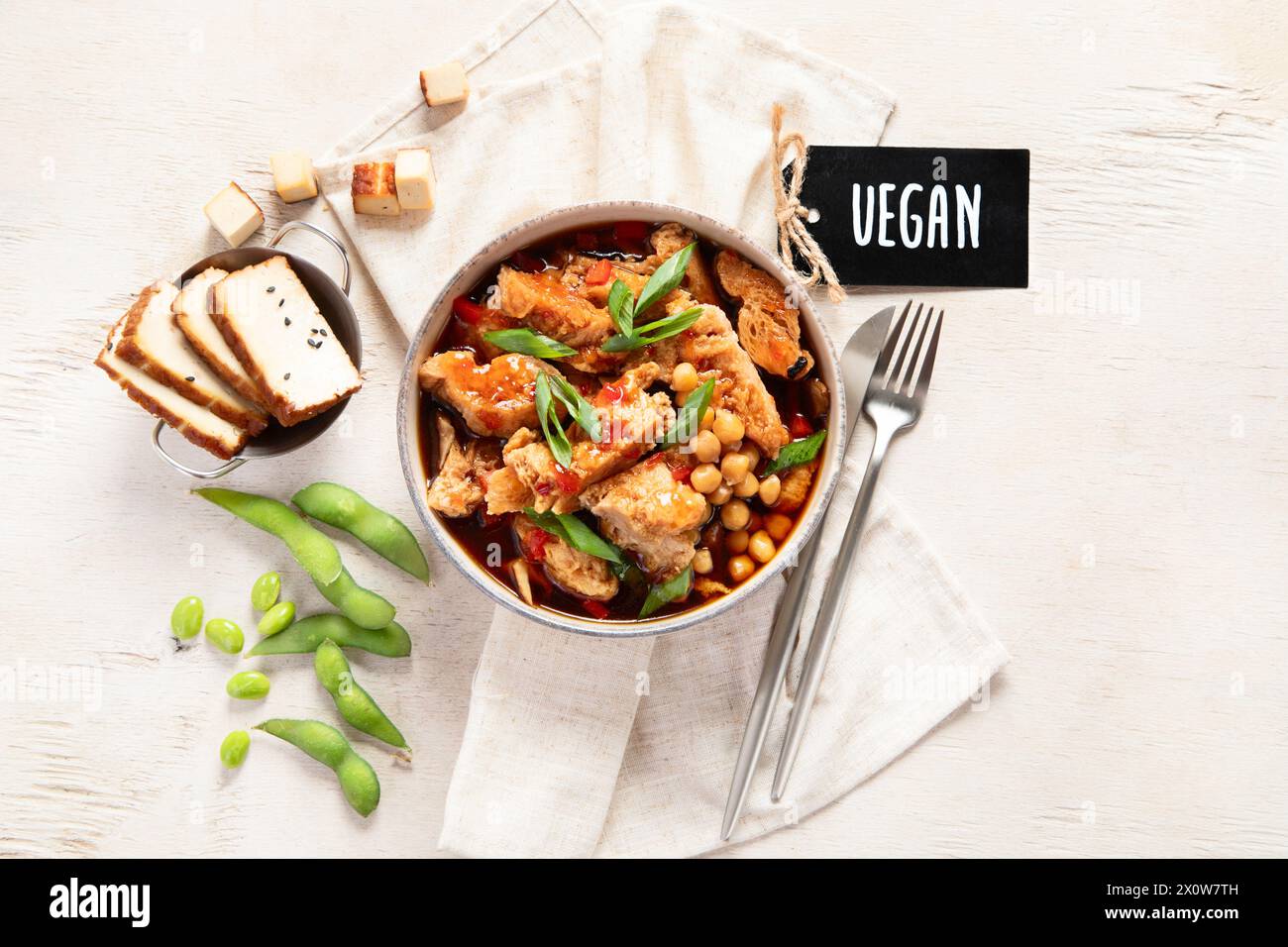 Soia con carne di soia, cipolla e tofu su sfondo di legno chiaro. Cibo vegano. Vista dall'alto Foto Stock