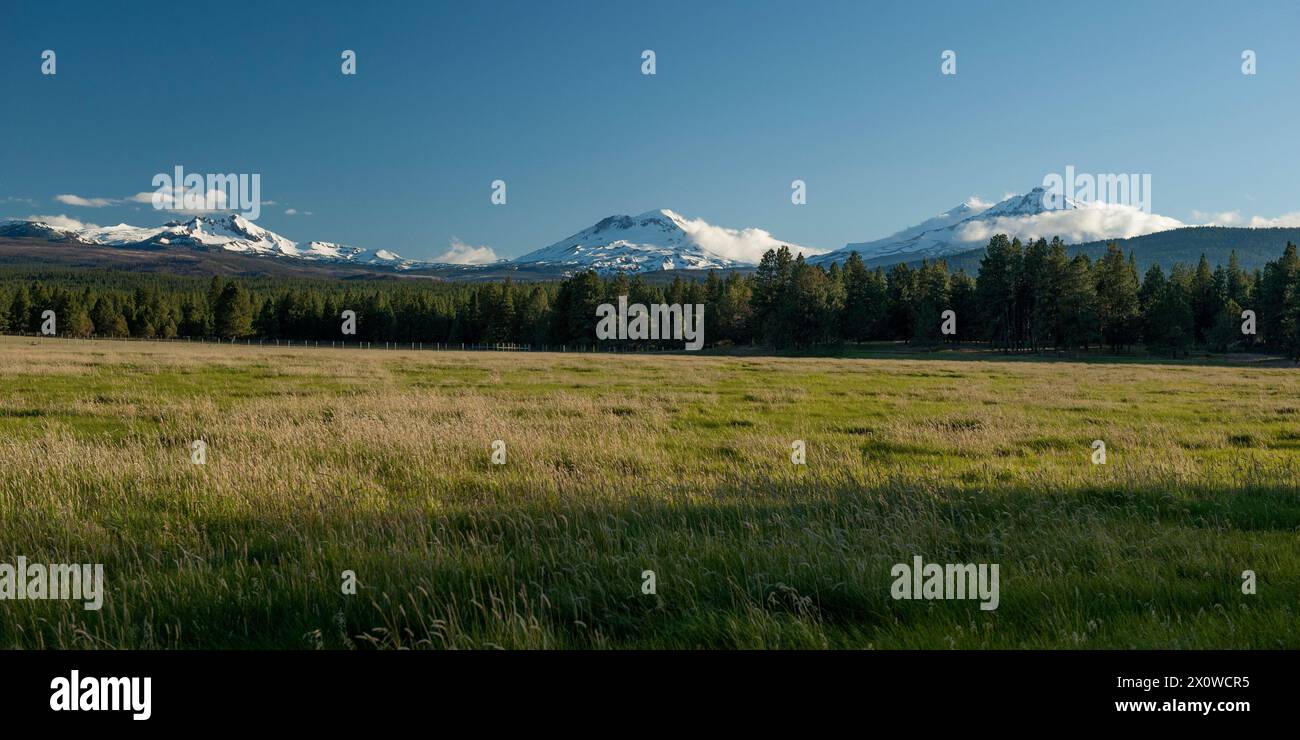 Le tre Sorelle dell'Oregon (centro e destra) e Broken Top (sinistra) viste dalla città di Sisters, Oregon Foto Stock