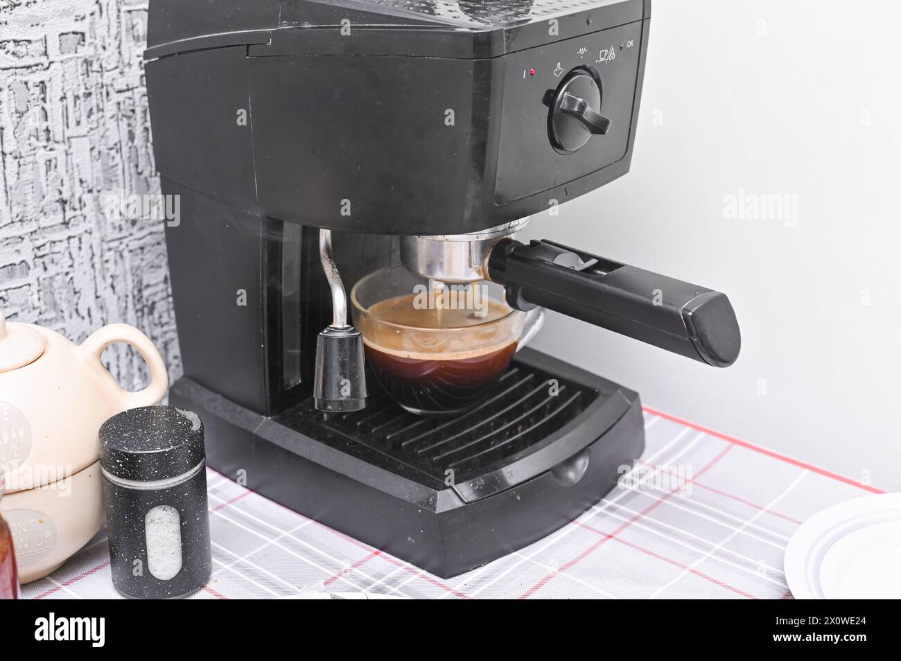 Una macchina per il caffè versa il caffè in una tazza di vetro Foto Stock