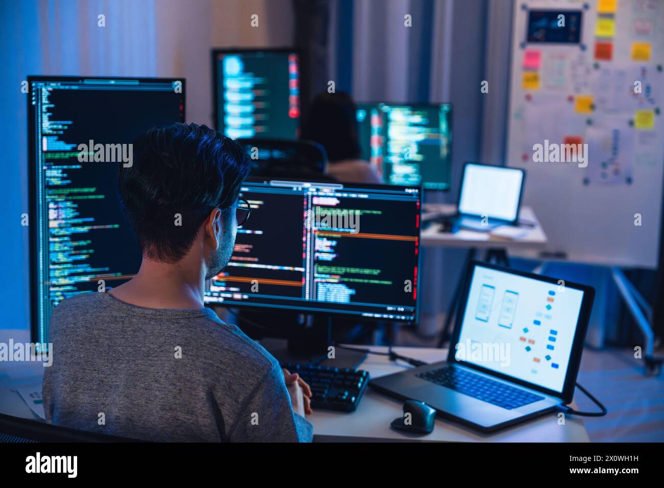 Team di sviluppatori asiatici e indiani devops che lavora sulla codifica di promgram con computer software di notte in ufficio Foto Stock