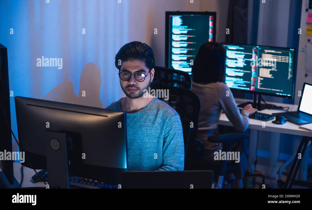 Team di sviluppatori asiatici e indiani devops che lavora sulla codifica di promgram con computer software di notte in ufficio Foto Stock