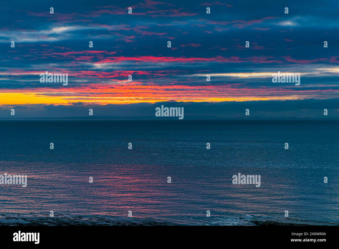Un leggero bagliore rossastro sul lato inferiore del coperchio nuvoloso Foto Stock