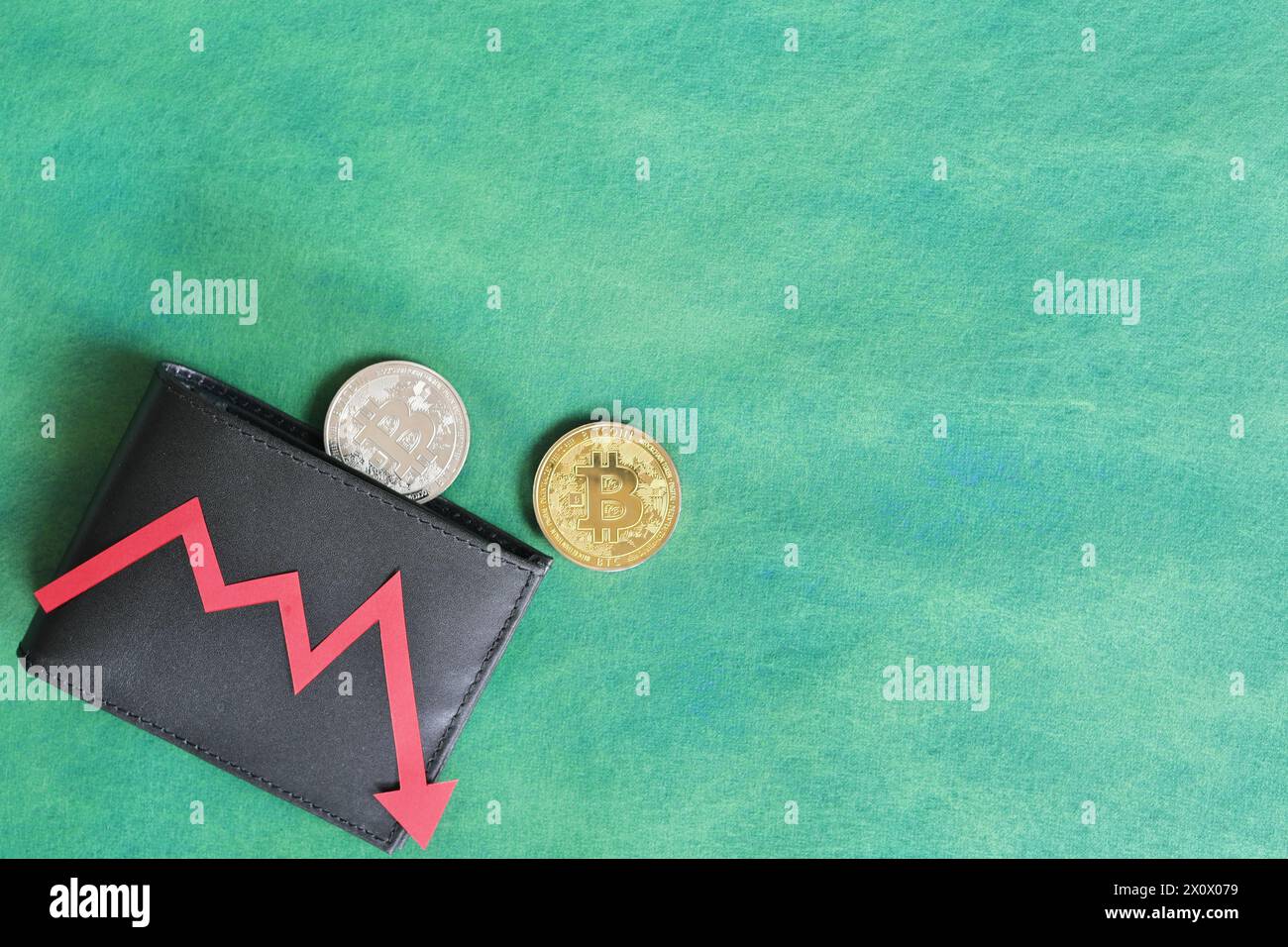 Mano umana che tiene nero un portafoglio con bitcoin e freccia rossa verso il basso e moneta all'interno. Il concetto di corsa e riduzione dei prezzi della criptovaluta. Foto Stock