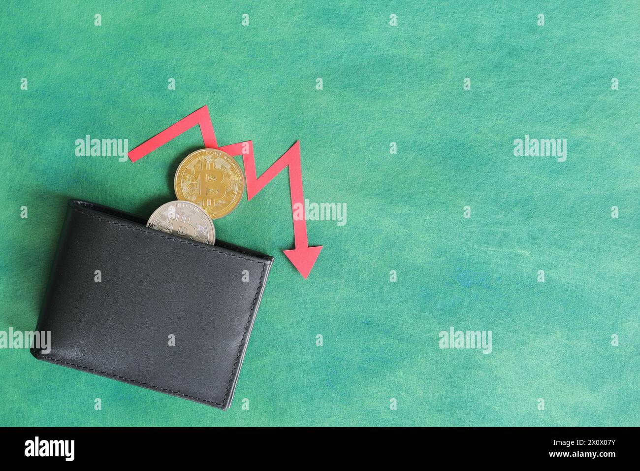 Mano umana che tiene nero un portafoglio con bitcoin e freccia rossa verso il basso e moneta all'interno. Il concetto di corsa e riduzione dei prezzi della criptovaluta. Foto Stock