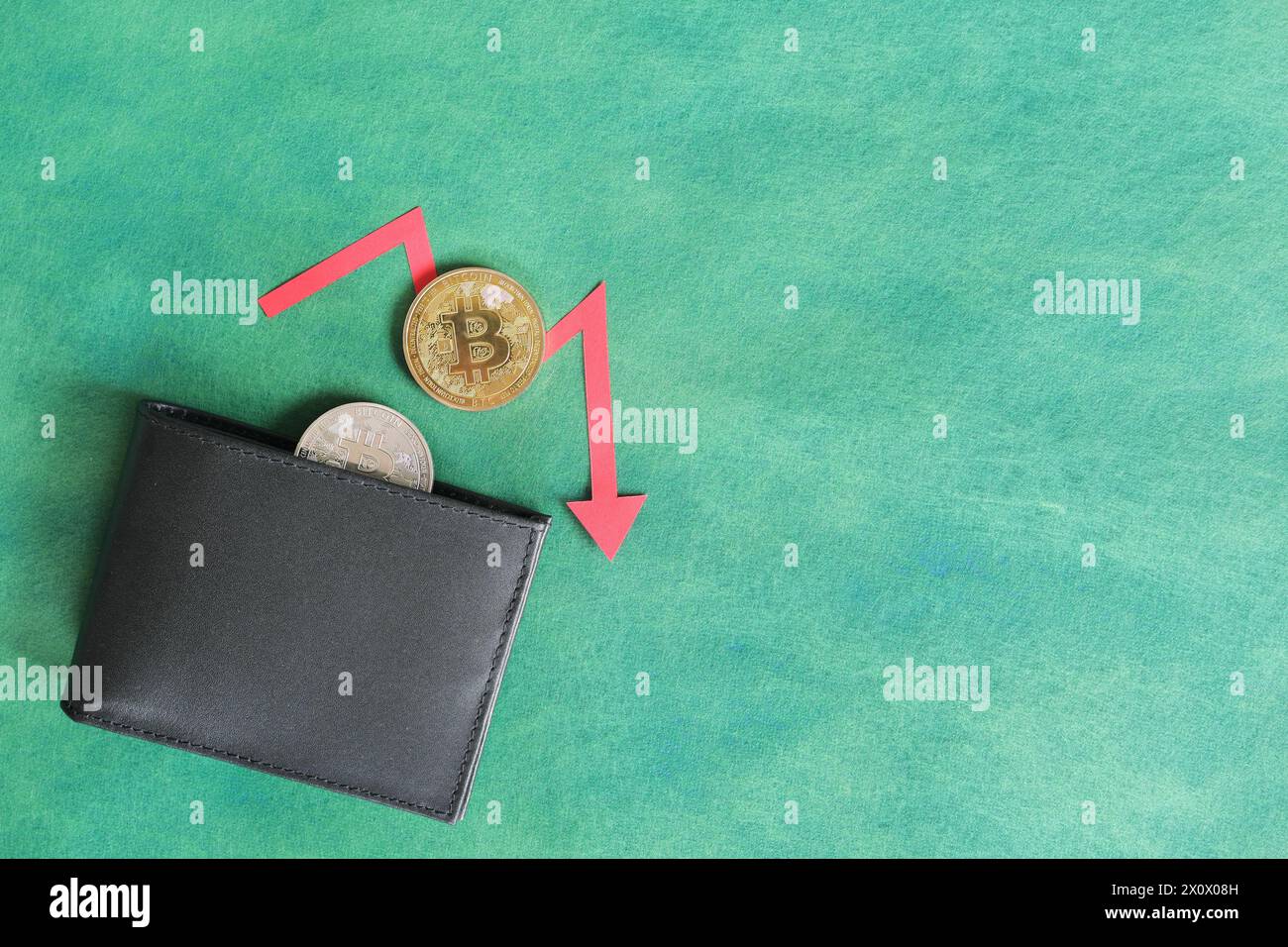 Mano umana che tiene nero un portafoglio con bitcoin e freccia rossa verso il basso e moneta all'interno. Il concetto di corsa e riduzione dei prezzi della criptovaluta. Foto Stock