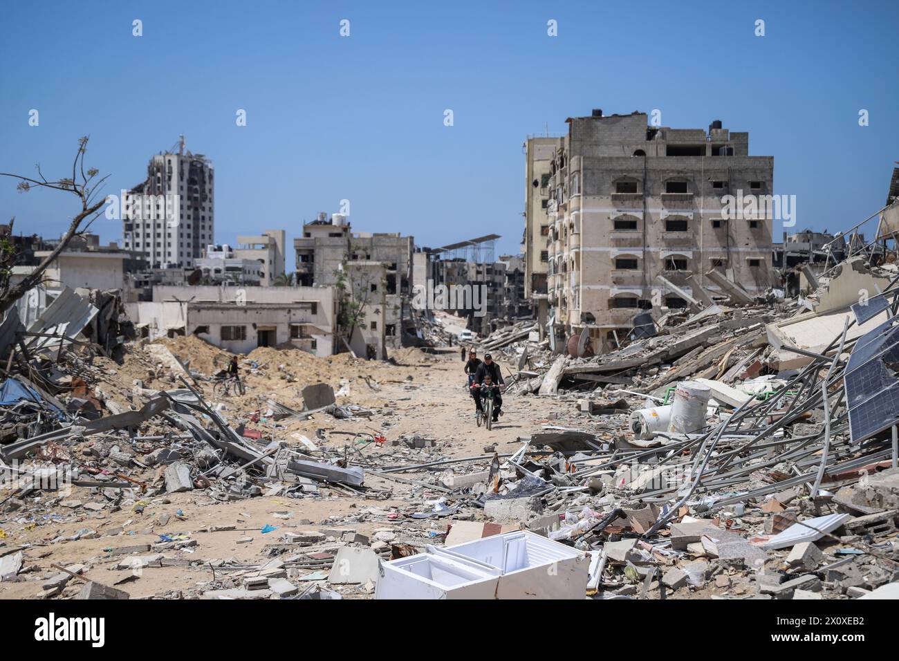 (240414) -- GAZA, 14 aprile 2024 (Xinhua) -- persone cavalcano i detriti nella città di Gaza, 13 aprile 2024. Il movimento di resistenza islamica (Hamas) ha annunciato sabato di aver risposto ai mediatori in Egitto e Qatar per il proposto cessate il fuoco nella Striscia di Gaza e ha ribadito le sue richieste. (Foto di Mohammed Ali/Xinhua) Foto Stock