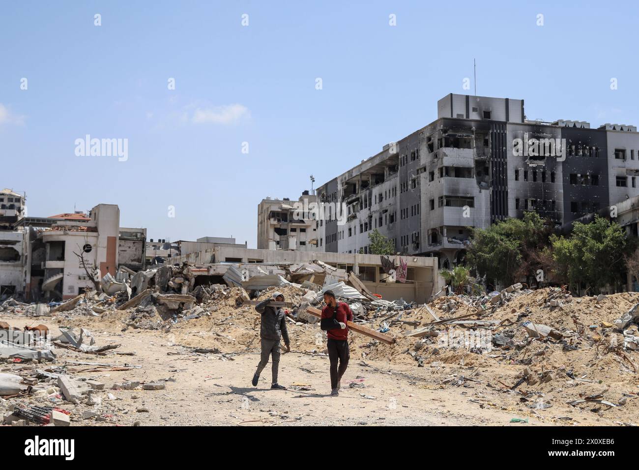 (240414) -- GAZA, 14 aprile 2024 (Xinhua) -- la gente cammina davanti ai detriti nella città di Gaza, 13 aprile 2024. Il movimento di resistenza islamica (Hamas) ha annunciato sabato di aver risposto ai mediatori in Egitto e Qatar per il proposto cessate il fuoco nella Striscia di Gaza e ha ribadito le sue richieste. (Foto di Mohammed Ali/Xinhua) Foto Stock