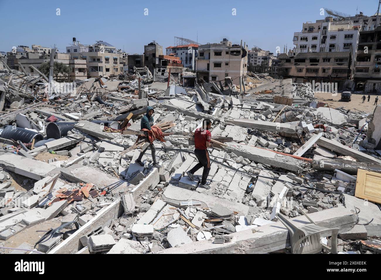 (240414) -- GAZA, 14 aprile 2024 (Xinhua) -- la gente cammina sui detriti nella città di Gaza, 13 aprile 2024. Il movimento di resistenza islamica (Hamas) ha annunciato sabato di aver risposto ai mediatori in Egitto e Qatar per il proposto cessate il fuoco nella Striscia di Gaza e ha ribadito le sue richieste. (Foto di Mohammed Ali/Xinhua) Foto Stock