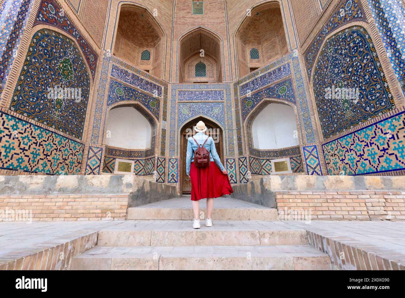 Vista posteriore di Young Woman a Bukhara, Uzbekistan Madrasa Mir-i-Arab minareto e torre Kalyan. Traduzione sulla moschea: "Poi Kalyan Mosque" Foto Stock