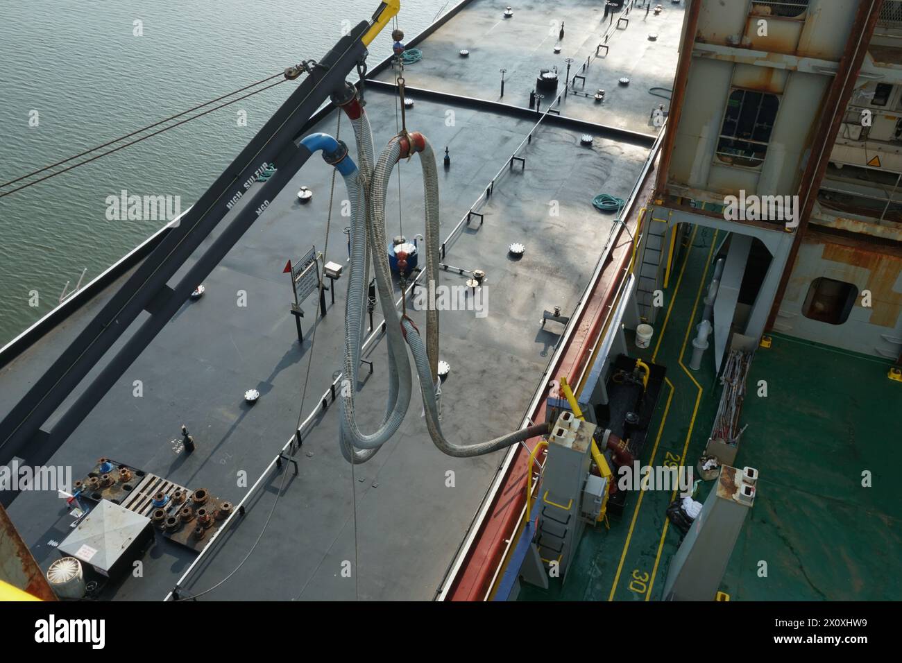 Vista aerea sul tubo flessibile del carburante della chiatta del bunker sulla gru collegata al serbatoio nella stazione di bunker con valvole e collettori. Foto Stock