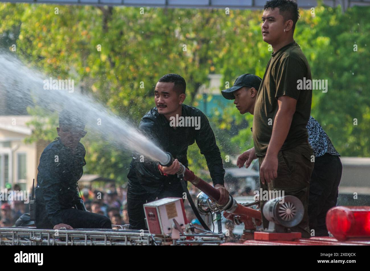 I vigili del fuoco, su un camion dei vigili del fuoco, spruzzano acqua sulla folla durante il festival cambogiano del capodanno. Wat Phnom, Phnom Penh, Cambogia. © Kraig Lieb Foto Stock