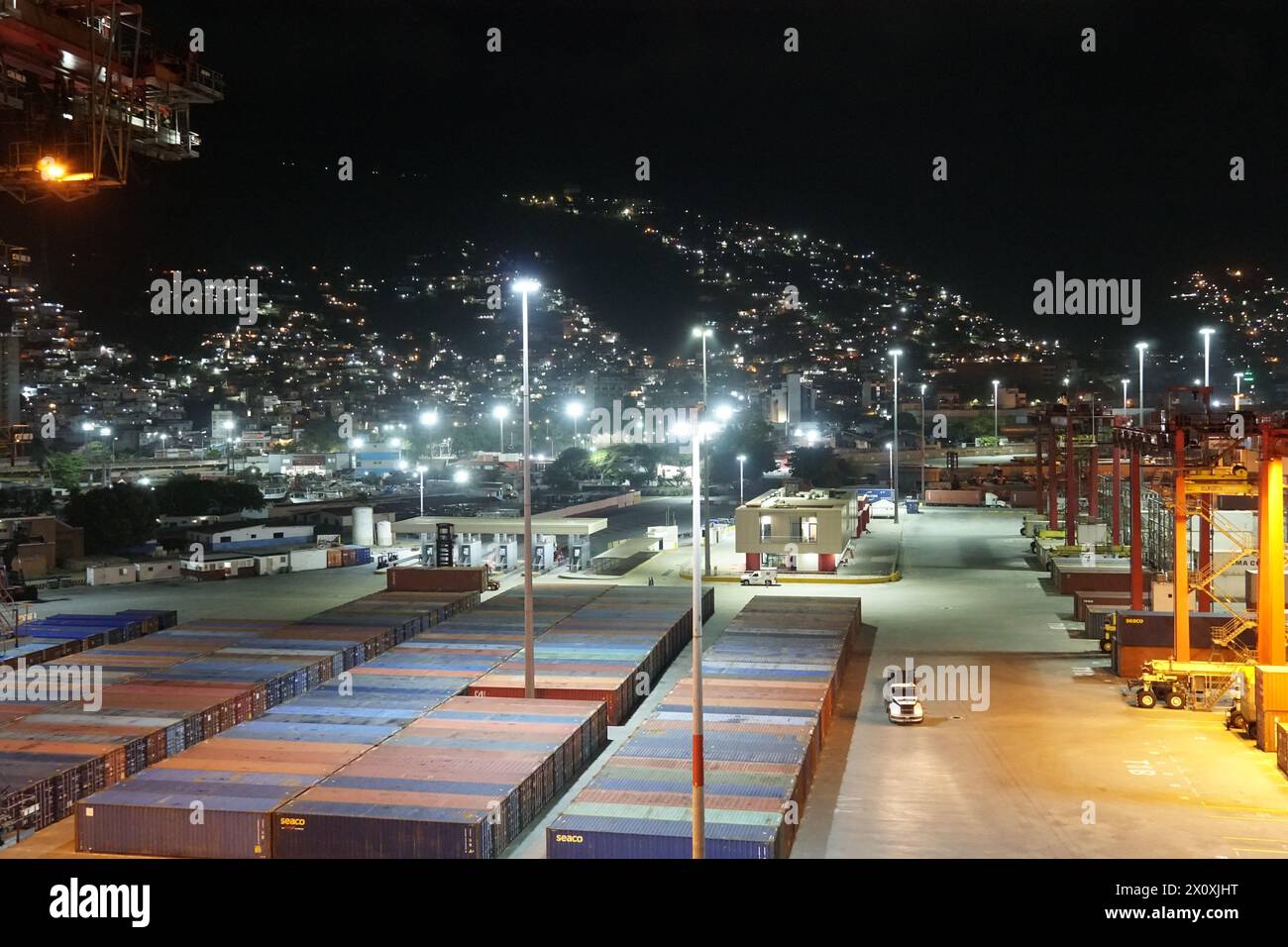Vista notturna sul terminal container nel porto di la Guairá osservata dalla nave da carico ormeggiata sotto le gru a cavalletto. Foto Stock