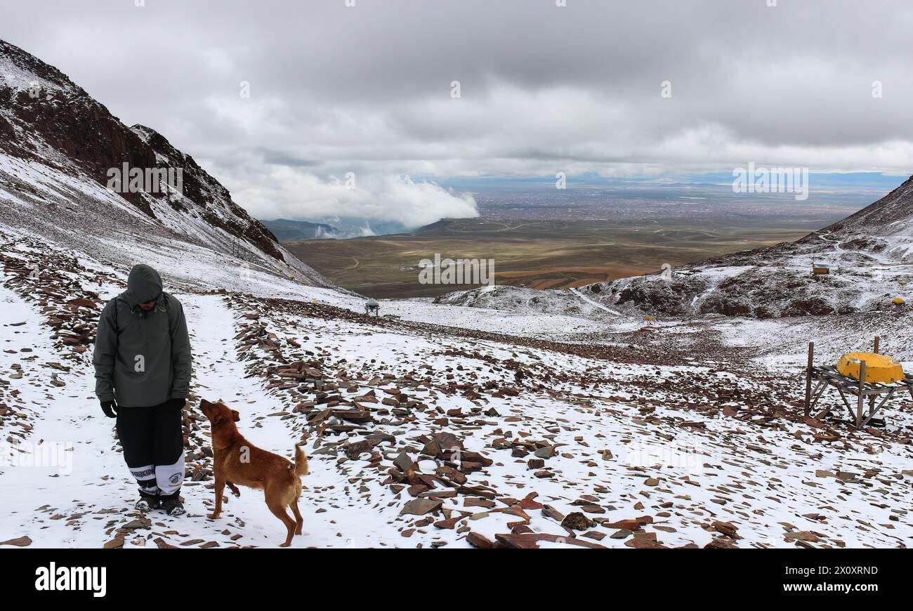 Uomo accompagnato da un cane in cima alla vetta di Chacaltaya, a 5421 metri sul livello del mare, dove c'era la stazione sciistica più alta del mondo. Nelle Ande Foto Stock