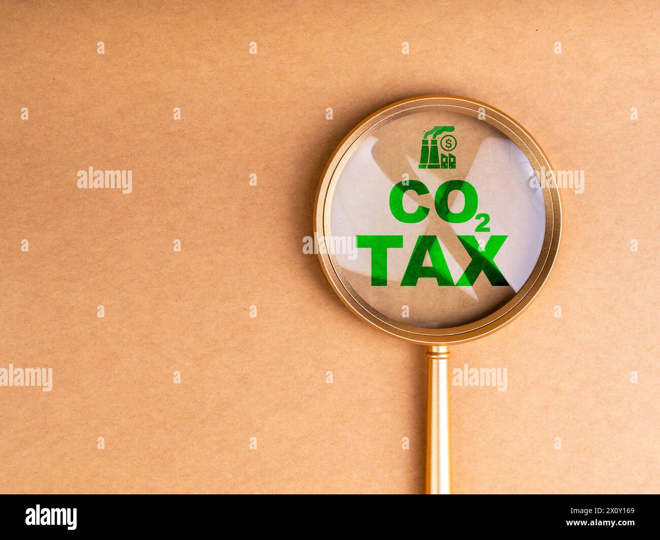 Tassa sul carbonio. Icona di fabbrica industriale e testo verde, "TASSA CO2" in lente di ingrandimento su sfondo riciclato con spazio di copia. Ambientale, sociale Foto Stock