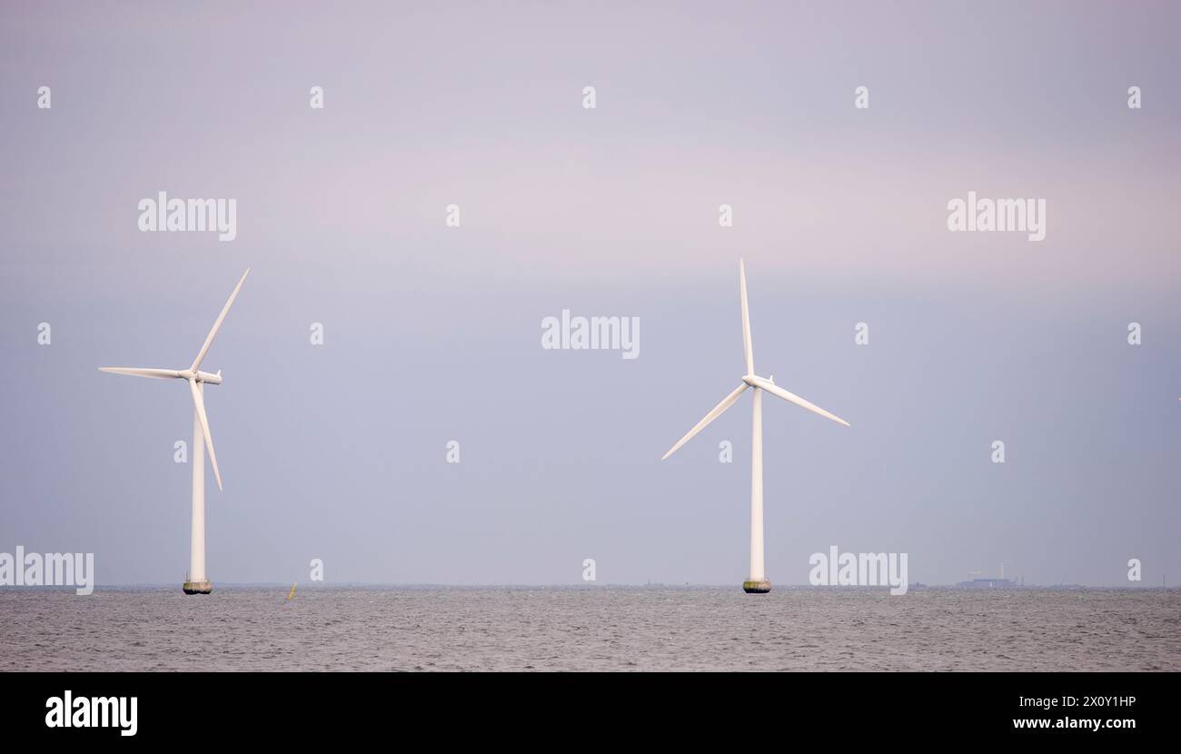 Questa immagine stock presenta una coppia di torreggianti turbine eoliche offshore che si innalzano dal Mar Baltico, simbolo di energia sostenibile e ingegneria moderna. Foto Stock