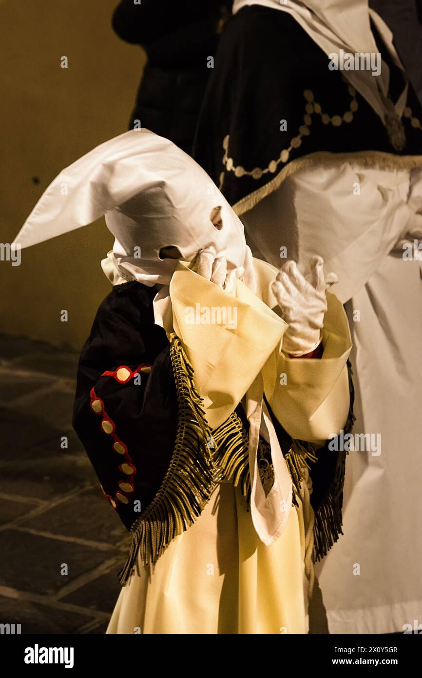 Bambino con cappuccio e guanti grandi durante la famosa processione del venerdì Santo Foto Stock