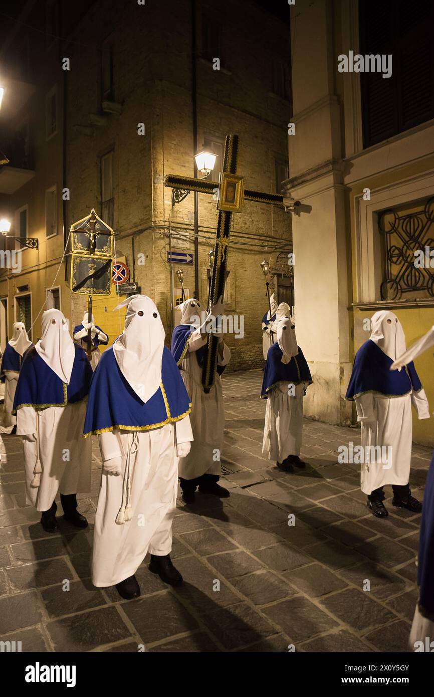 I penitenti incappucciati durante la famosa processione del venerdì Santo a Chieti (Italia) portano la croce con l'effigie di Gesù Foto Stock