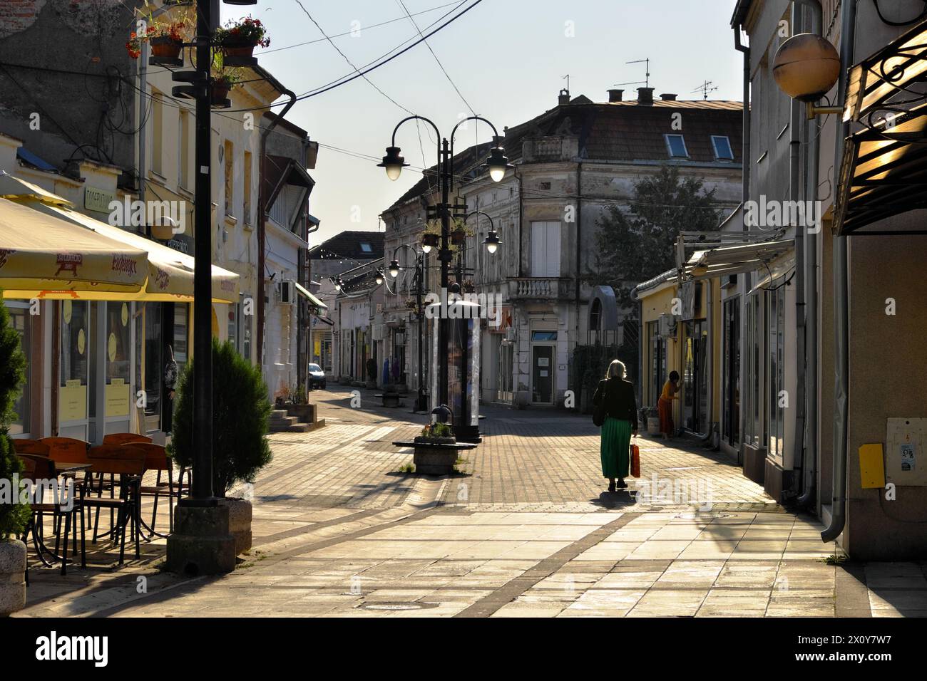 Donna sola che cammina lungo i negozi chiusi della via pedonale Kneza Miloša nella città di Valjevo, in Serbia Foto Stock