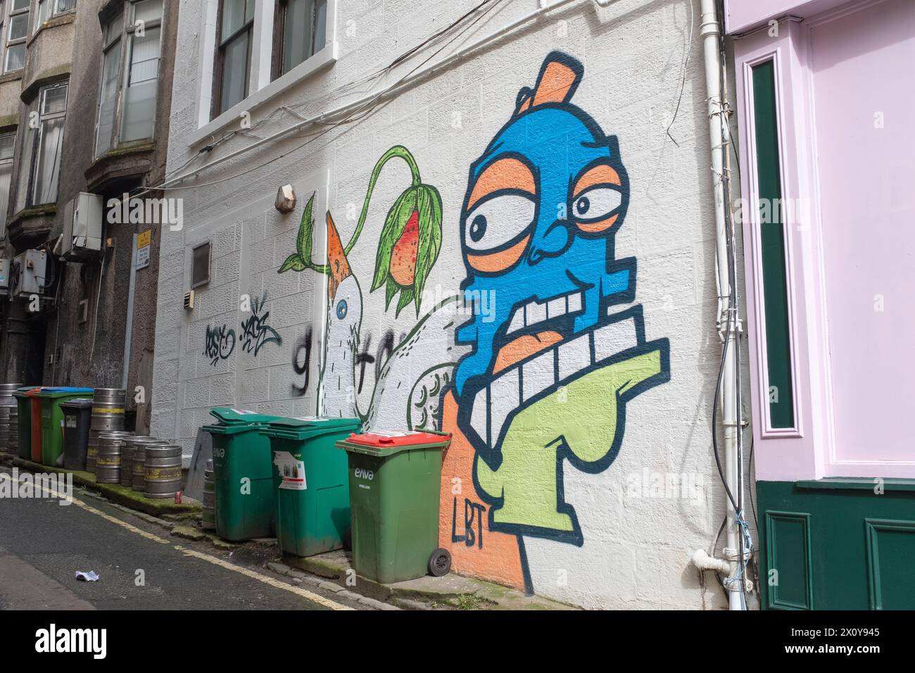 Graffiti e murales di Big Heid di Oh Panda in un vicolo accanto a Hope Street, nel centro di Glasgow, Scozia. È possibile vedere una collezione di bidoni per le impennate. Foto Stock