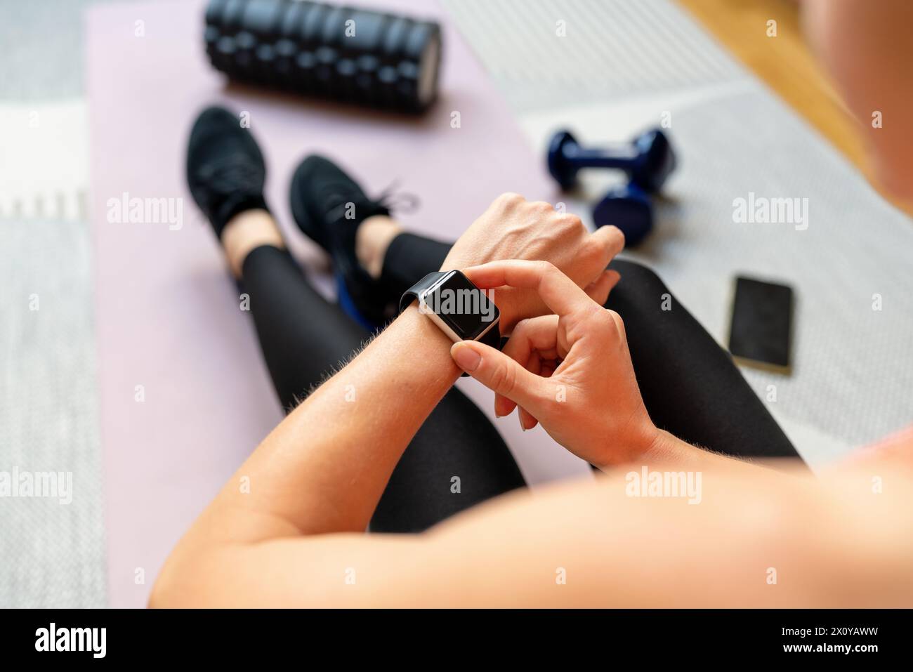 Donna sportiva che prepara un programma di allenamento utilizzando il suo smartwatch. Tracker fitness. Tecnologia indossabile Foto Stock