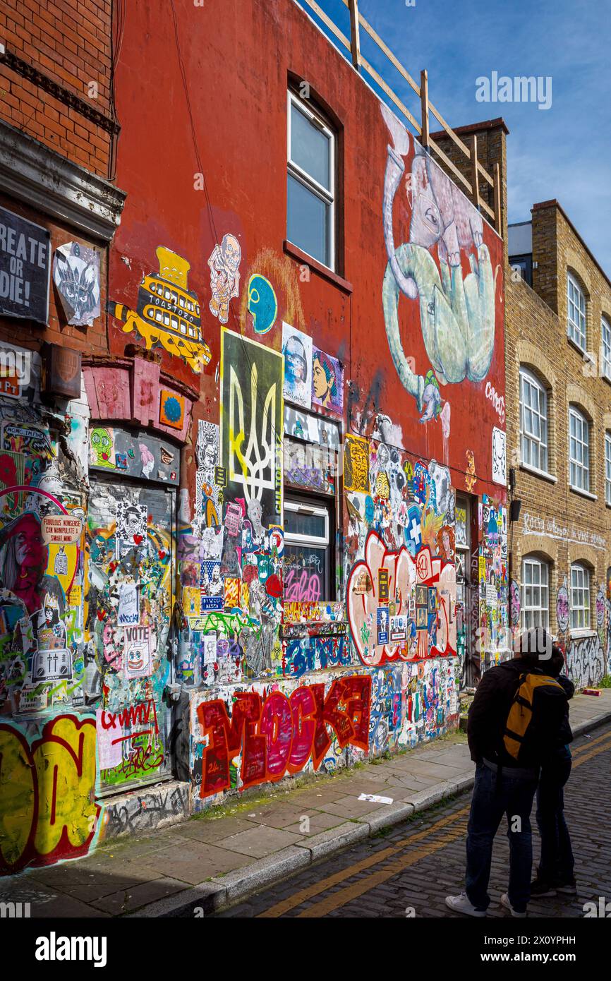 Brick Lane Street Art London, passanti che guardano la Street art in una piccola strada vicino a Brick Lane, Shoreditch, East London. Foto Stock