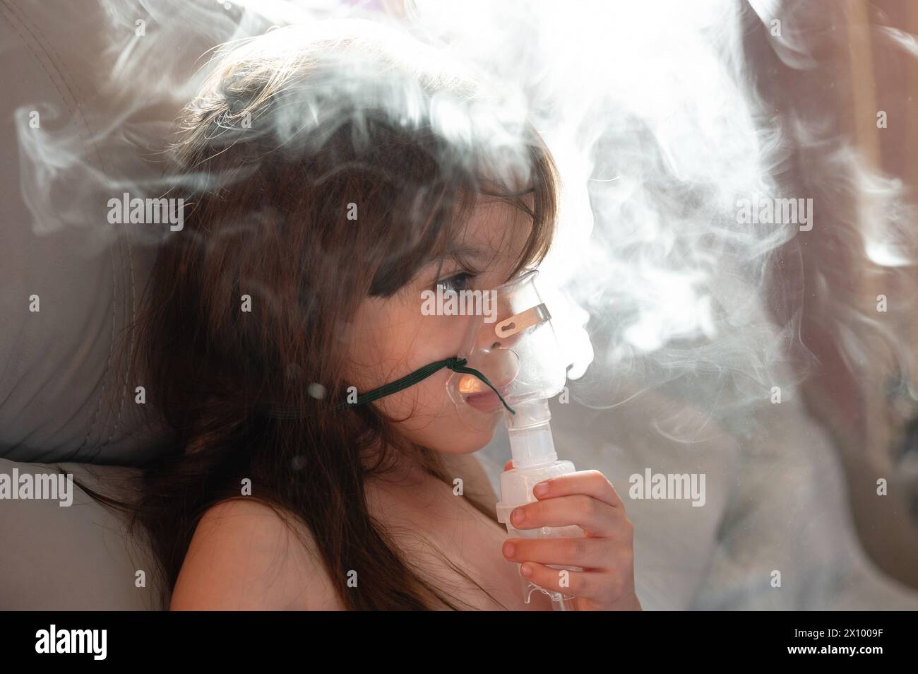 Ragazzina sotto trattamento medico utilizzando maschera nebulizzatore in fumo di fondo vapore Foto Stock