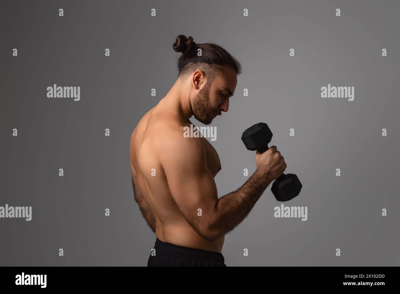 Uomo concentrato che solleva manubri in palestra Foto Stock