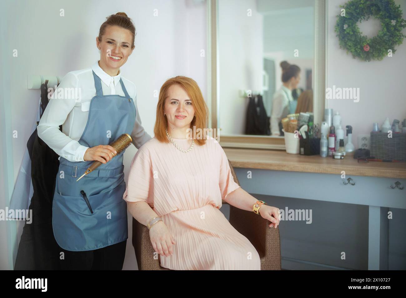 lavoratrice di parrucchiere donna in moderno studio di bellezza con spazzola per capelli e cliente. Foto Stock