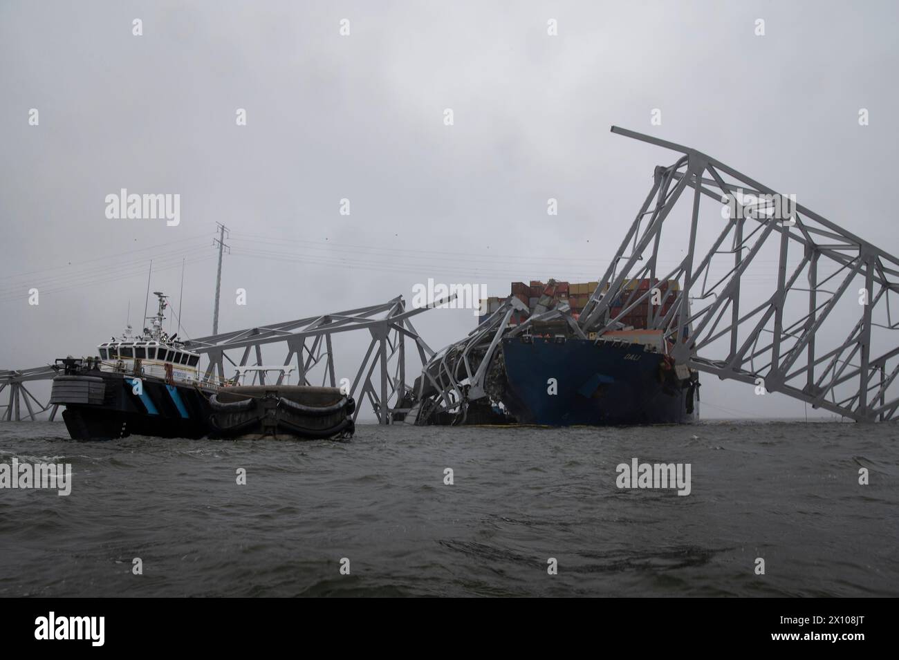 Dundalk, Stati Uniti d'America. 3 aprile 2024. Una nave di salvataggio accede ai danni della portaerei MV Dali incastrata nelle capriate d'acciaio del Francis Scott Key Bridge crollato bloccando il canale di Fort McHenry, il 3 aprile 2024, vicino a Dundalk, Maryland. Il ponte fu colpito dalla nave portacontainer di 984 piedi il 26 marzo e crollò uccidendo sei lavoratori. Crediti: PO2 Alejandro Rivera/Guardia Costiera degli Stati Uniti/Alamy Live News Foto Stock