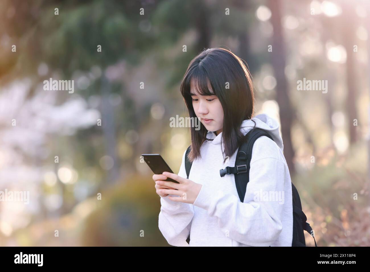 Concetto di viaggio per studentesse delle scuole superiori e universitarie che giocano su smartphone e scambiano messaggi SNS con gli amici Foto Stock