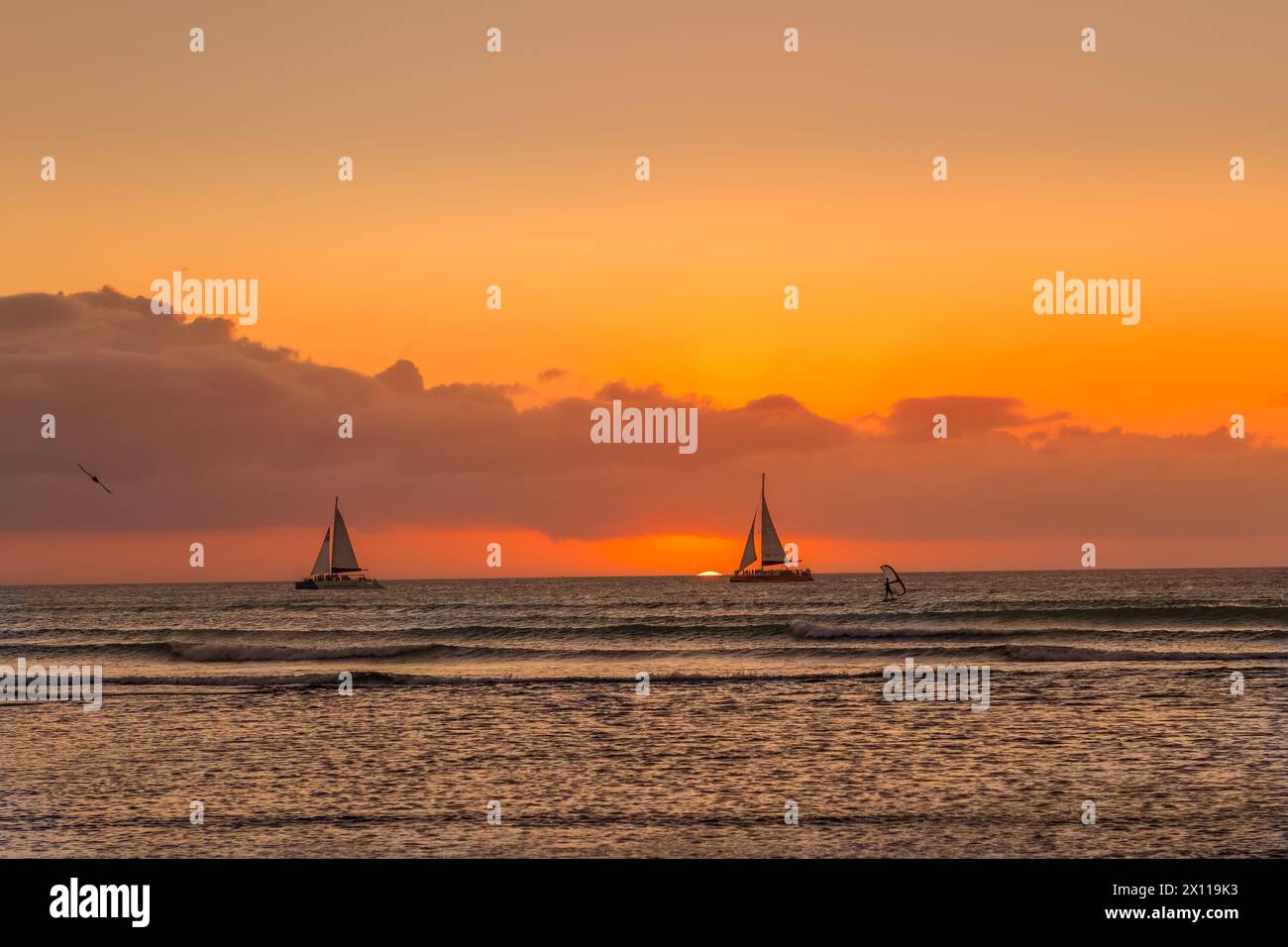 Barche a vela e windsurf all'orizzonte con il sole che tramonta ad Aruba Foto Stock