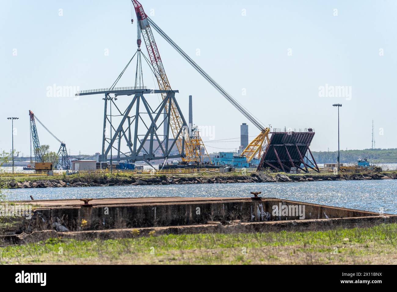 Key Bridge Response 2024 i salvatori dello Unified Command utilizzano la chiatta con gru Chesapeake 1000 per spostare un grande pezzo di acciaio di supporto dal crollo di Francis Scott Key Bridge, 14 aprile 2024, a Baltimora, Maryland. La Chesapeake 1000 è la più grande gru galleggiante sulla costa orientale, e la rimozione di questi grandi pezzi aiuterà ad aprire un canale ad accesso limitato che consente il traffico di navi a senso unico verso il porto di Baltimora. La rimozione di detriti e rottami è in corso a sostegno di una priorità assoluta per aprire in modo sicuro ed efficiente il canale di Fort McHenry. (Foto U.S. Army Corps of Engineers di Charles del Foto Stock