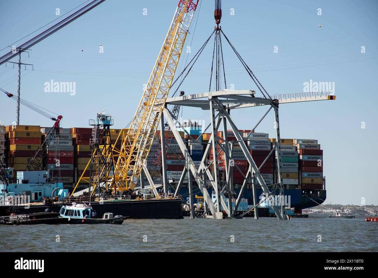 Key Bridge Response 2024 i salvatori dello Unified Command utilizzano la chiatta della gru Chesapeake 1000, per spostare un grande pezzo di acciaio di supporto dal crollato Francis Scott Key Bridge, 14 aprile 2024, a Baltimora, Maryland. La Chesapeake 1000 è la più grande gru galleggiante sulla costa orientale, e la rimozione di questi grandi pezzi aiuterà ad aprire un canale ad accesso limitato che consente il traffico di navi a senso unico verso il porto di Baltimora. La rimozione di detriti e rottami è in corso a sostegno di una priorità assoluta per aprire in modo sicuro ed efficiente il canale di Fort McHenry. Foto Stock
