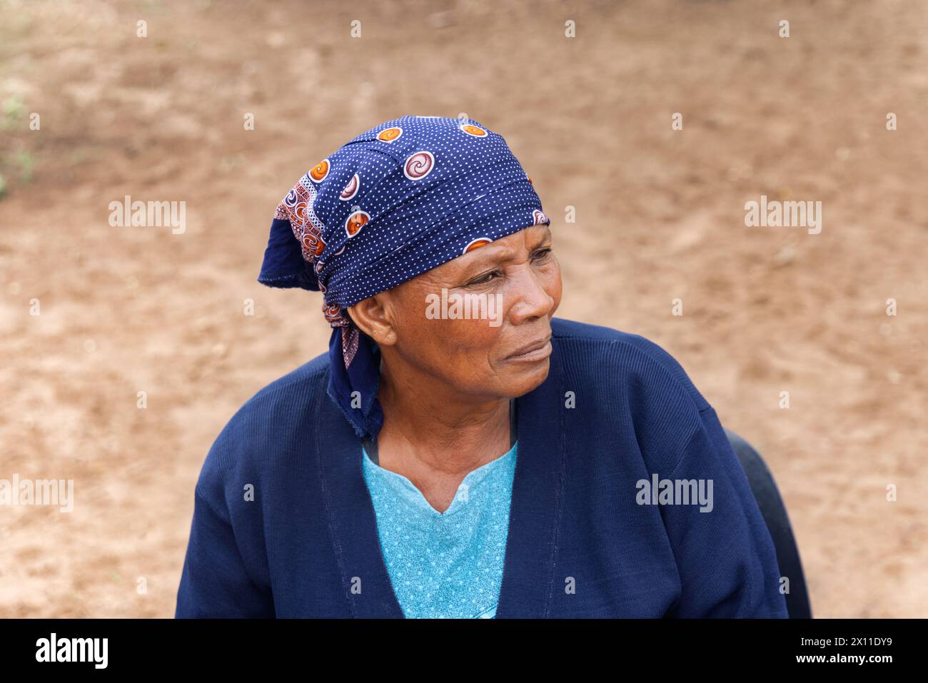 ritratto di una vecchia donna africana, seduta su una sedia nel cortile del villaggio Foto Stock