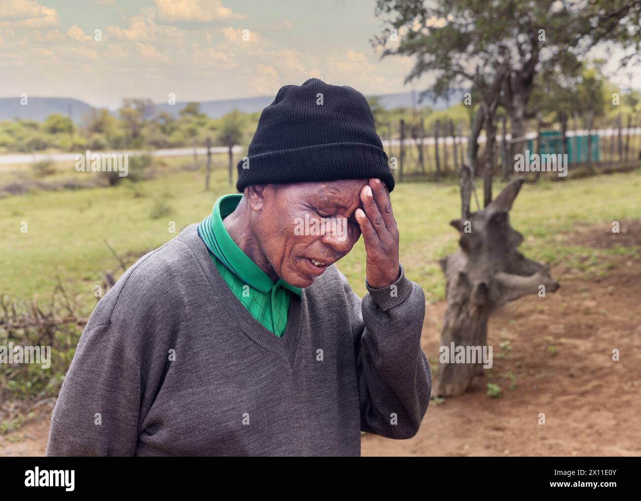 ritratto di un vecchio africano, con mal di testa e dimenticando le cose, nel cortile del villaggio Foto Stock