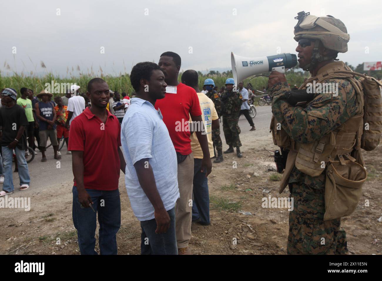 Clausele Barthold, linguista del Battalion Landing Team, 3rd Battalion, 2nd Marine Regiment, 22nd Marine Expeditionary Unit, parla con gli haitiani locali durante un'operazione per fornire cibo e acqua alla popolazione di Leogane, 19 gennaio 2010. Foto Stock