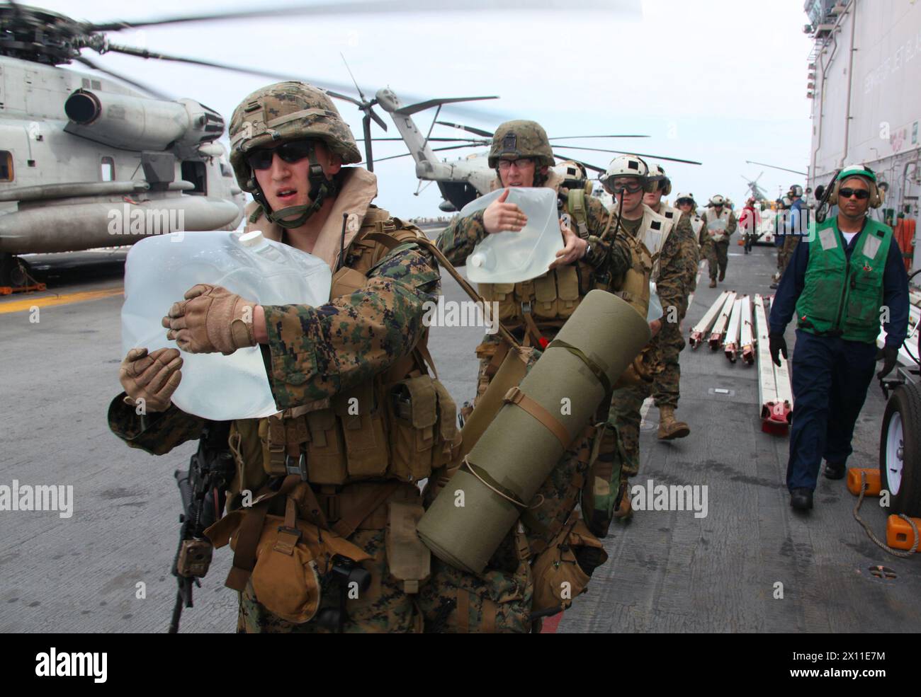 Marine con 3rd Battalion, 2nd Marine Regiment, Battalion Landing Team, 22nd Marine Expeditionary Unit trasportano acqua e rifornimenti sui CH-53 Super Stallions, 19 gennaio 2010. Il 22° MEU è imbarcato a bordo delle navi del Bataan Amphibious Ready Group vicino all'isola di Haiti per fornire assistenza umanitaria e soccorsi in caso di catastrofi sulla scia di un devastante terremoto che ha colpito il paese il 12 gennaio 2010. Foto Stock