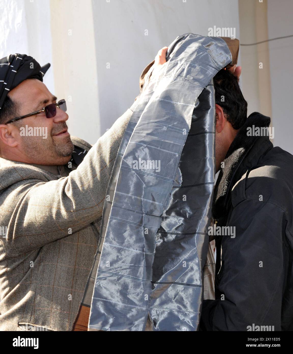 Il governo provinciale di Helmand Ghulab Mangal presenta simbolicamente un nuovo turbante a un membro della tribù Alikozai durante i negoziati di pace a Sangin, Afganistan, CA. 2010 Foto Stock