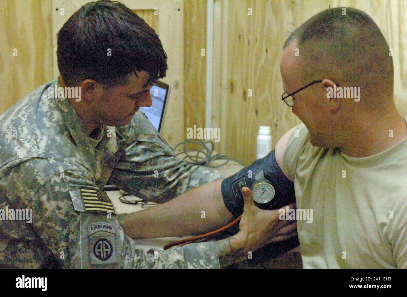 Brennan Griffin, specialista di assistenza sanitaria con 1st Attack Reconnaissance Battalion, 82nd Combat Aviation Brigade, controlla la pressione sanguigna su un paziente al nuovo Troop Medical Center presso contingency Operating base Speicher CA. 2004 Foto Stock