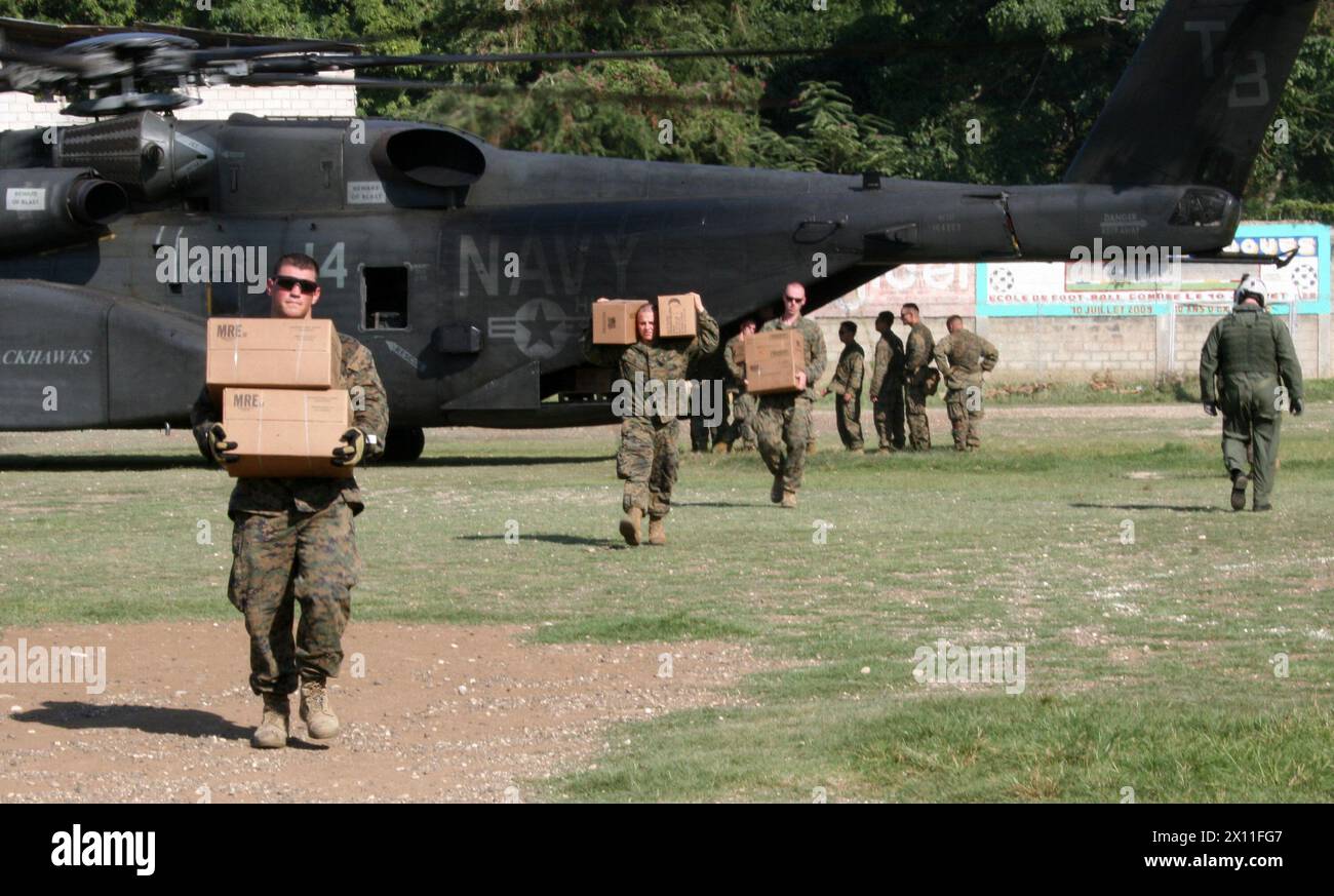 Marines from India Company, Battalion Landing Team, 3rd Battalion, 2nd Marine Regiment, 22nd Marine Expeditionary Unit, scaricare rifornimenti da un elicottero MH-53E Sea Dragon della Marina dall'Helicopter Mine Countermeasures Squadron 14, a Petit Goave, Haiti, 24 gennaio 2010. In risposta a un devastante terremoto che ha colpito il paese di Haiti, Marines e marinai della 22a MEU hanno iniziato a fornire forniture di soccorso e assistenza medica a sostegno dell'operazione Unified Response, 19 gennaio. Foto Stock