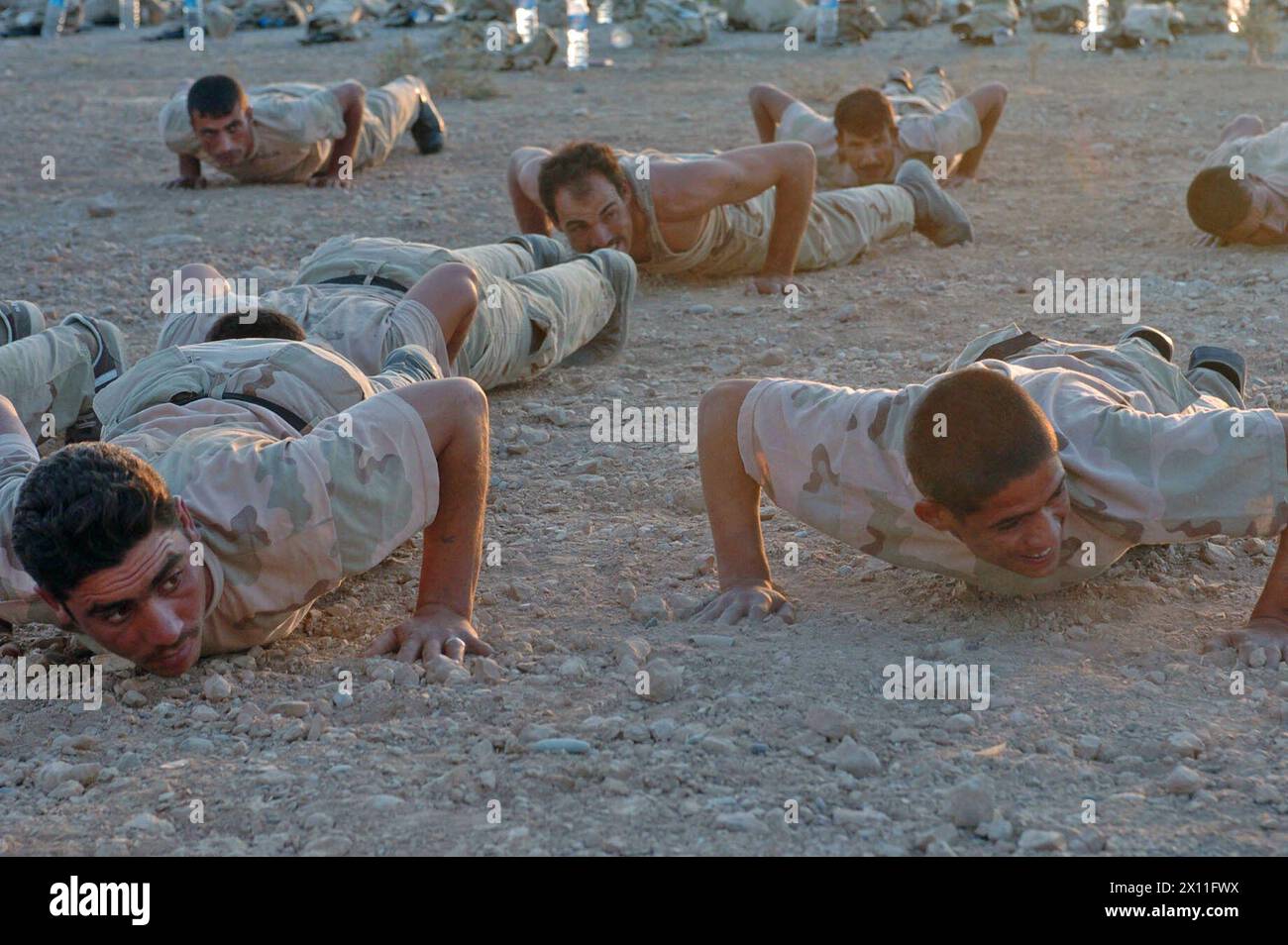 I soldati della Guardia Nazionale irachena fanno push-up durante l'allenamento fisico mattutino mentre frequentano un corso di addestramento di base di quattro settimane. Il corso è tenuto da soldati della compagnia C, 52nd Infantry Regiment, 3rd Brigade, 2nd Infantry Division (Stryker Brigade Combat Team) a Qayarrah, Iraq CA. 14 luglio 2004 Foto Stock