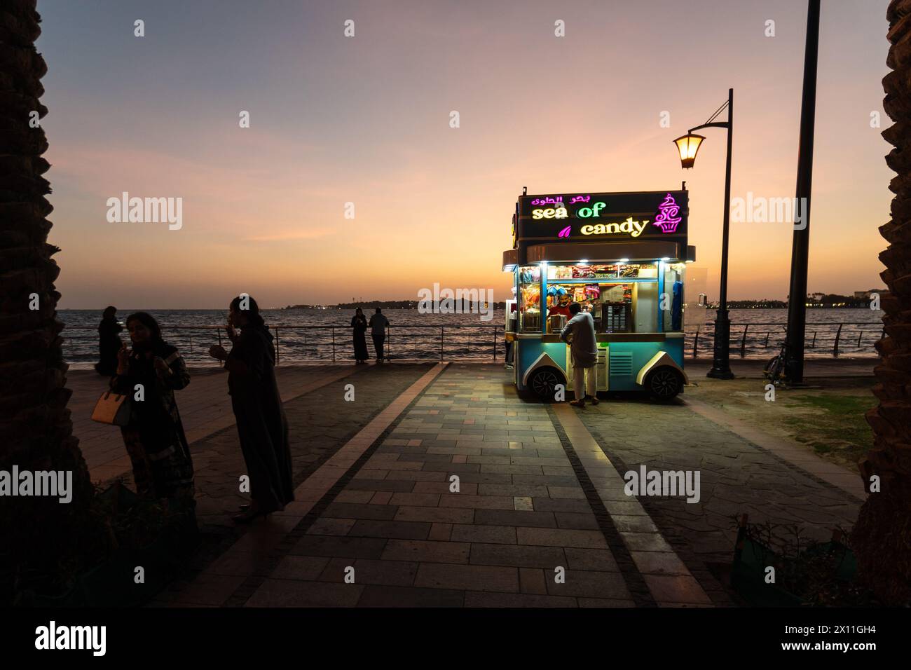 Jeddah, Arabia Saudita - gennaio 30 2023: Le persone si godono il crepuscolo presso la Corniche di al-Hamra con una bancarella di caramelle sul mare rosso in Arabia Saudita. Foto Stock